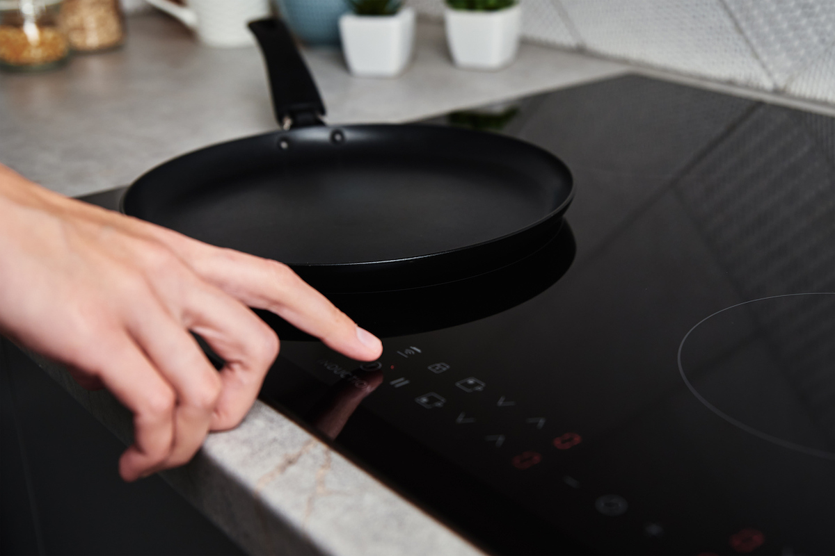 une main allumant une cuisinière électrique moderne avec technologie à induction