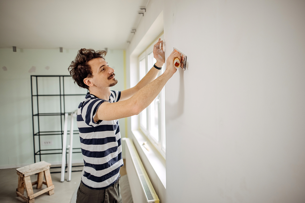 L'homme prépare le mur pour la peinture.