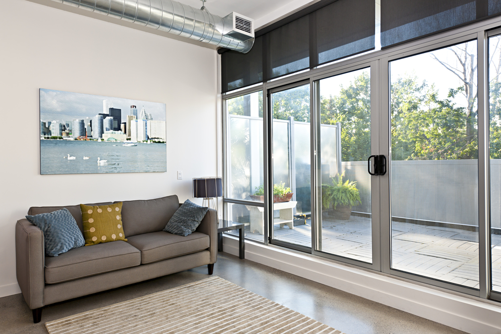 Sliding glass doors installed in a living room with a couch inside and a view of a small outdoor area.