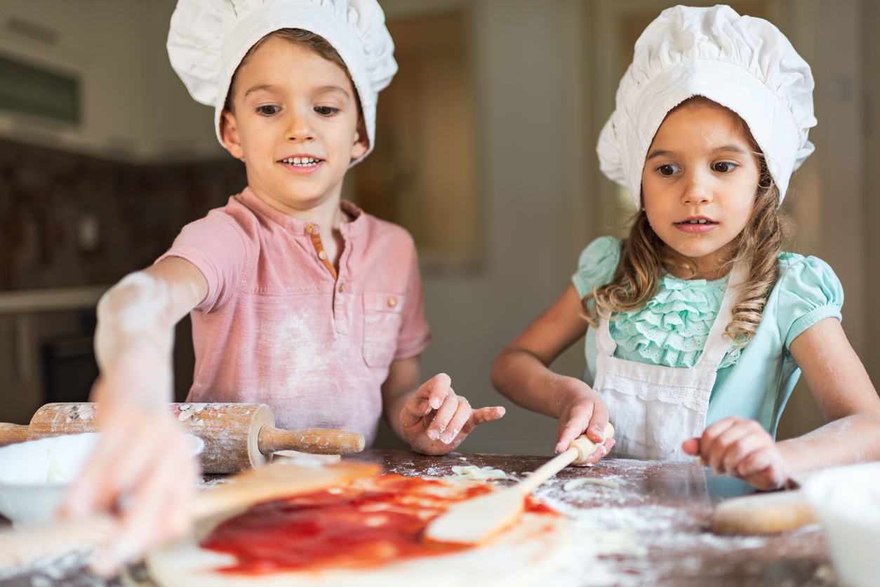 Un petit garçon et une petite fille préparent un repas dans la cuisine.