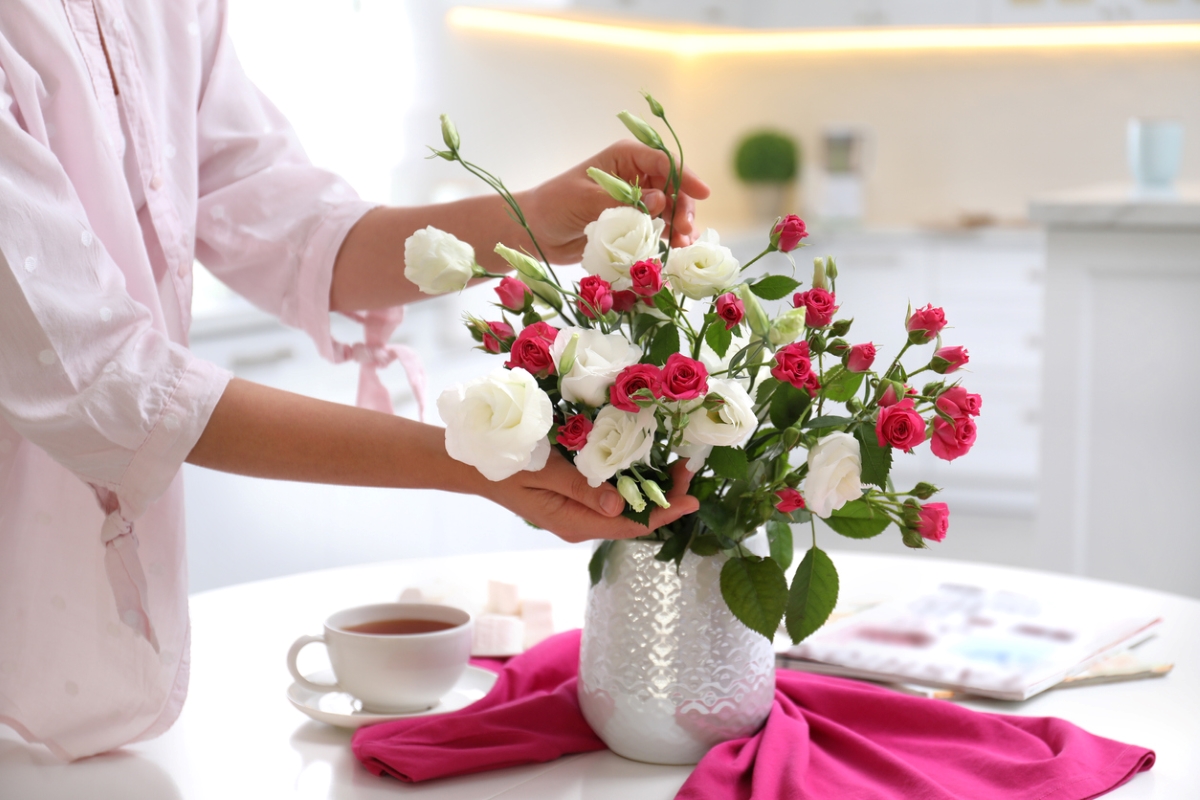 Woman touching up fresh flowers in vase