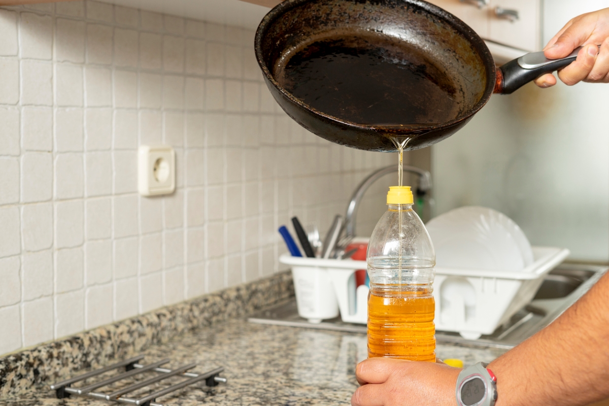 personne versant de l'huile de cuisson dans une bouteille