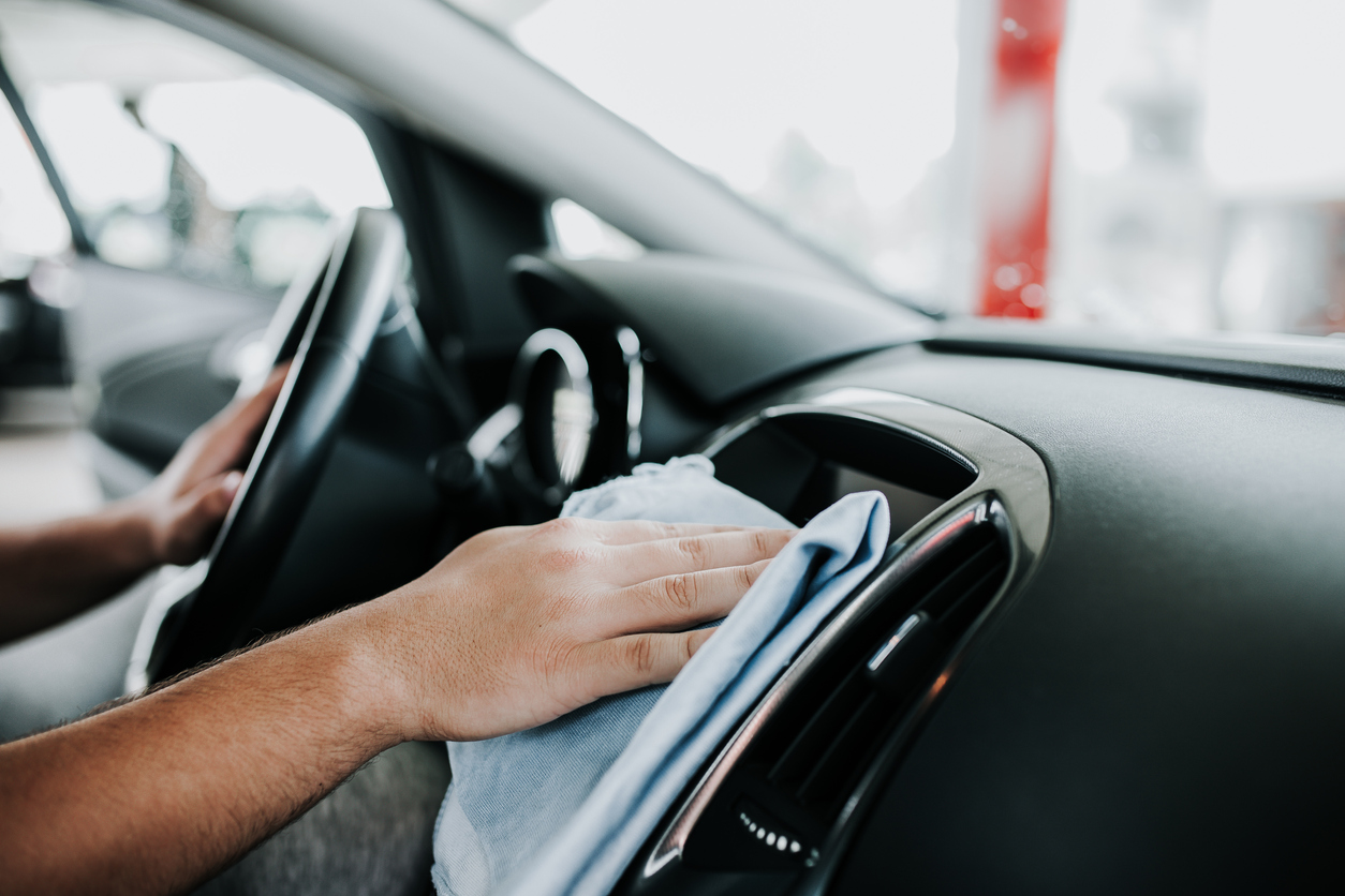 L'huile de coco est utilisée par un homme qui essuie le tableau de bord à l'intérieur d'une voiture