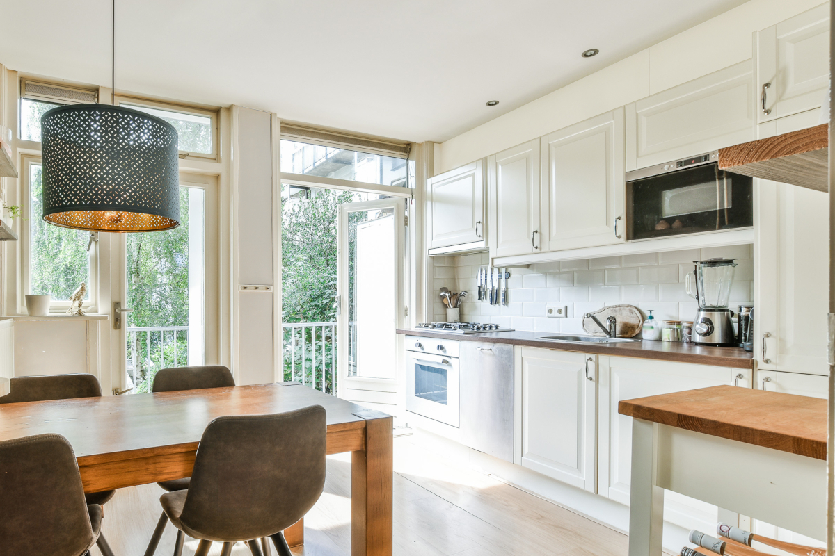 A bright kitchen soft white walls and cabinets and wood countertops.