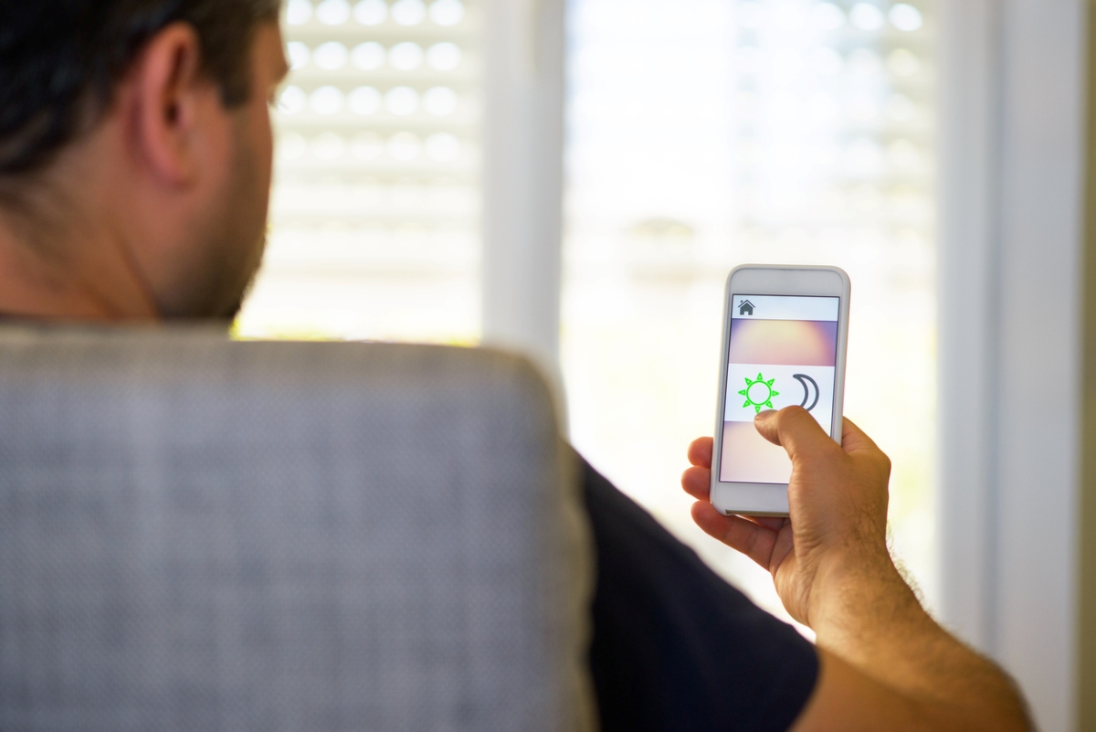 Homme à la maison utilisant un smartphone pour les réglages de jour et de nuit.