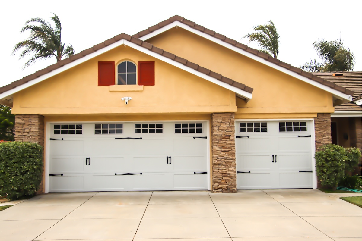 Clean white garage doors on a yellow house.