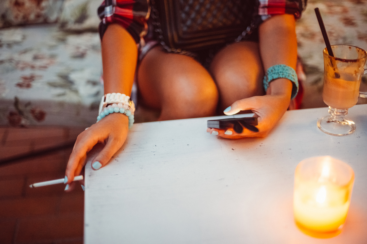 femme fumant une cigarette sur un balcon