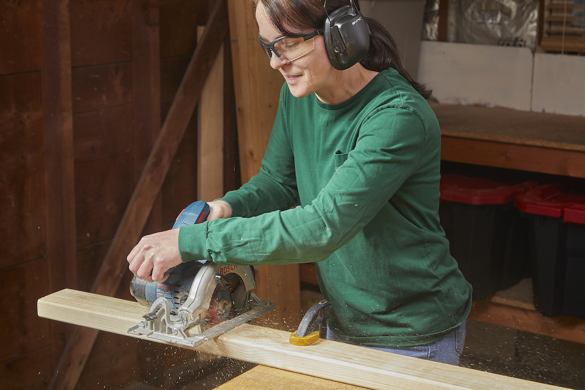 Femme effectuant une coupe transversale avec une scie circulaire.