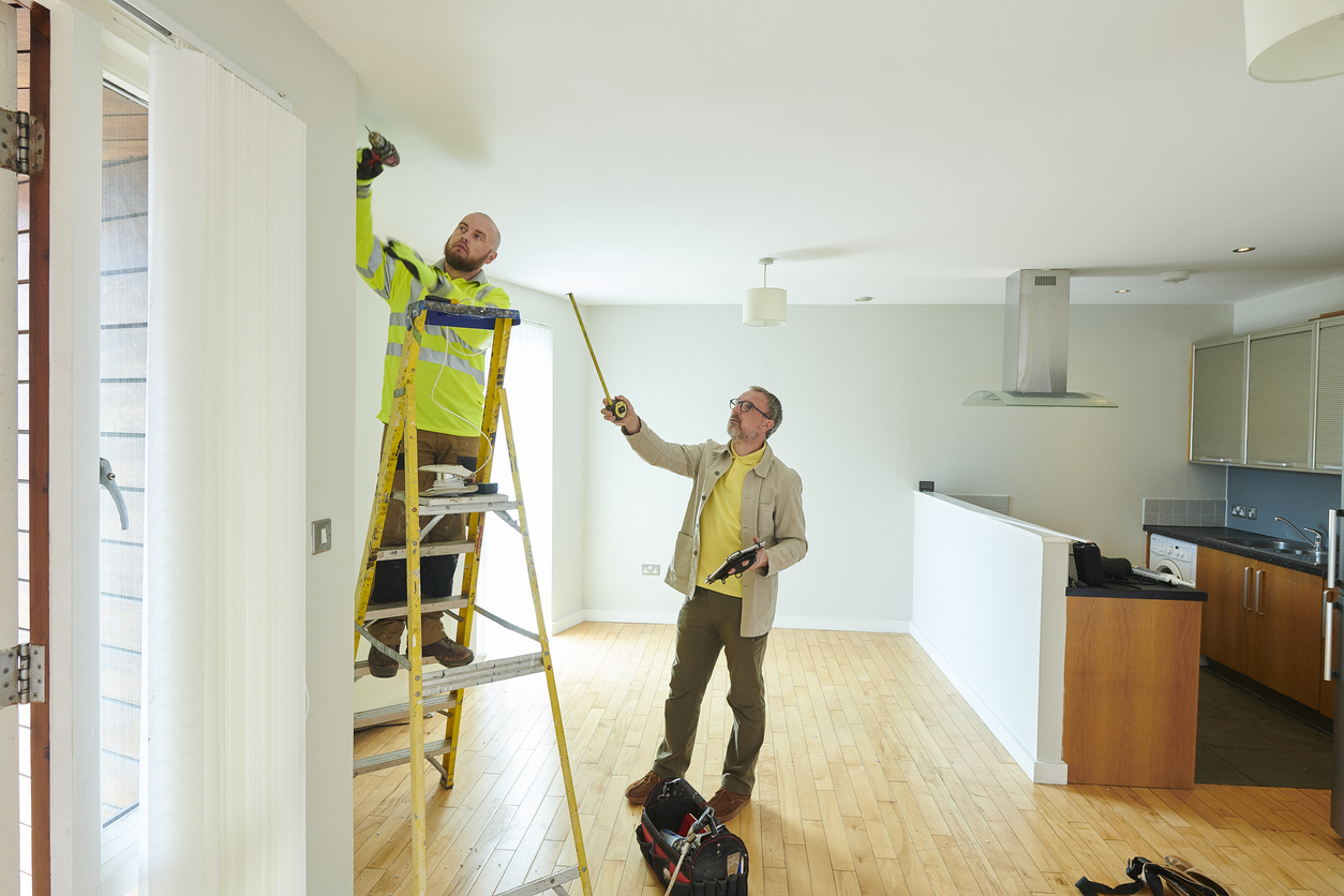 landlord talking to contractor in kitchen of apartment