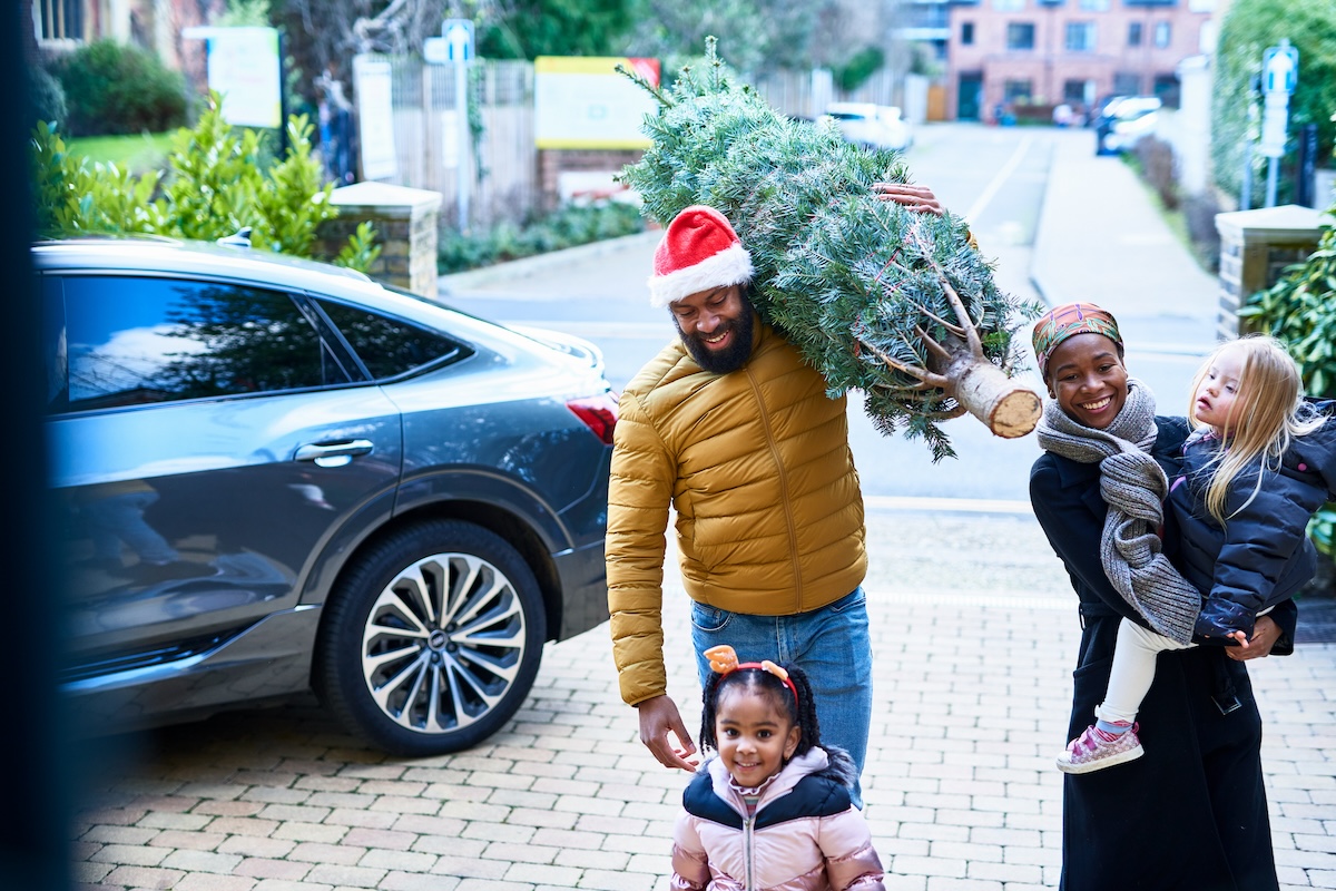 A family walking into their house with a fresh cut christmas tree.