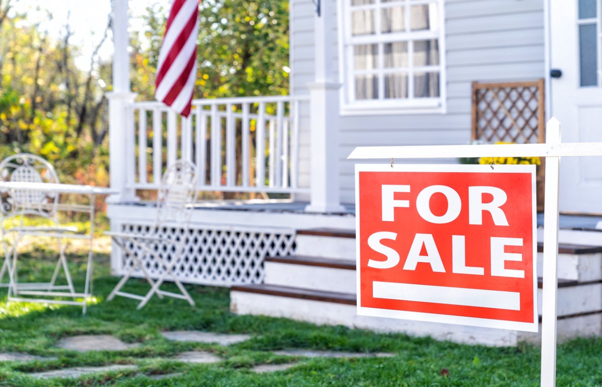 Home for sale real estate sign in front of beautiful new house.