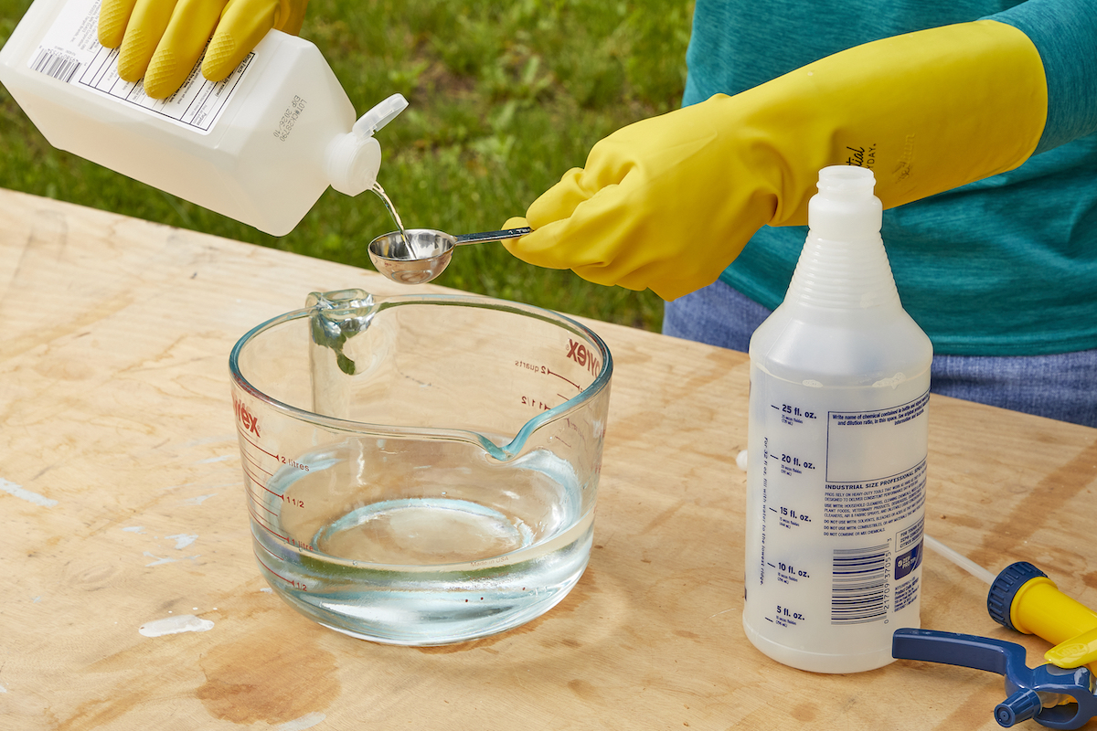 Woman measures rubbing alcohol into a measuring cup.