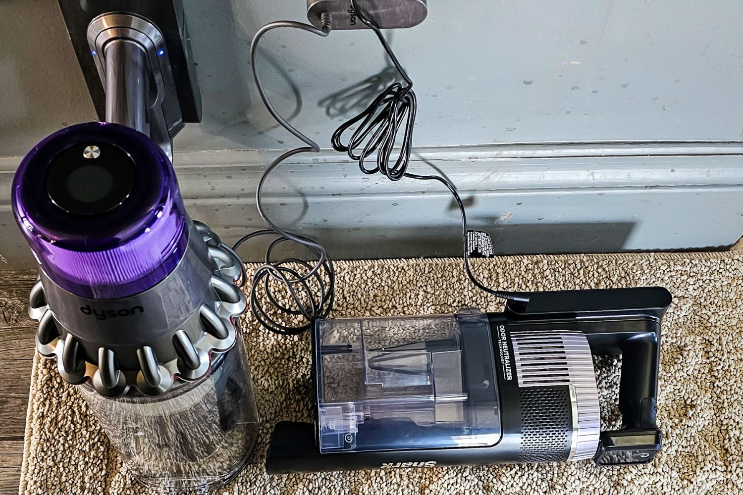 Batteries d'aspirateur sans fil Dyson vs Shark branchées sur une prise murale pour se charger pendant les tests.