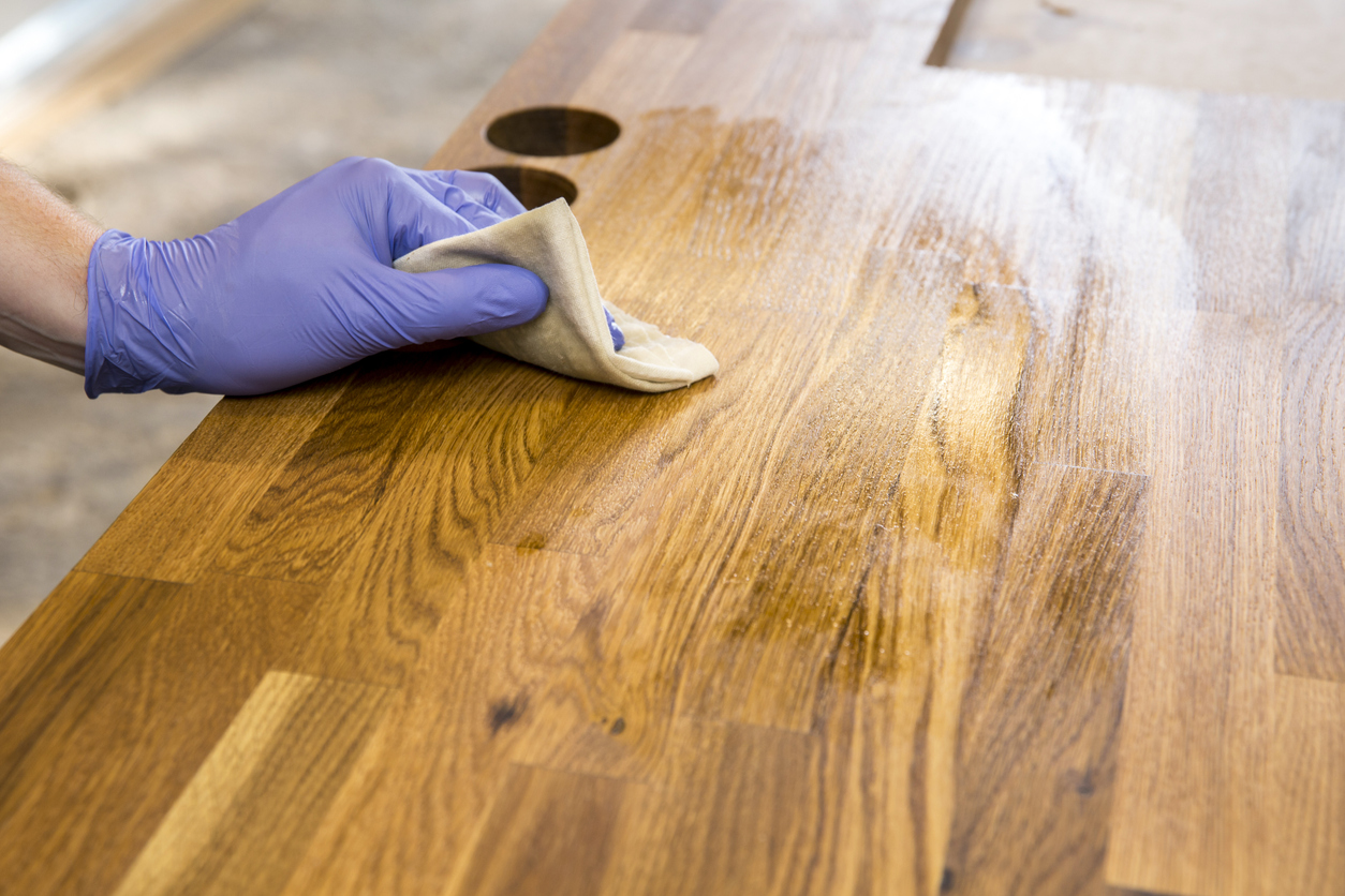 l'huile de coco utilise un essuyage manuel de la surface du bois avec un chiffon huilé portant un gant violet