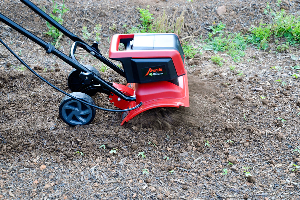 A close-up of the best electric tiller option tilling through dirt