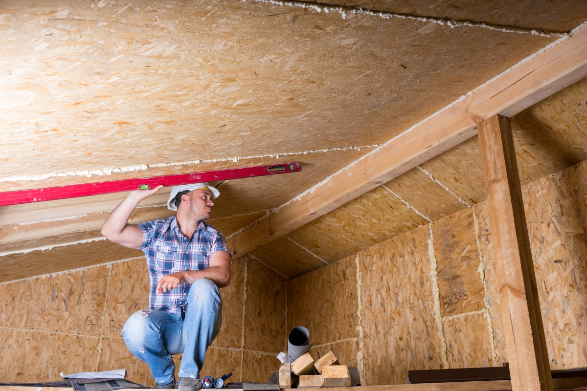 Contractor is holding a leveler on the ceiling to plan out where to install a skylight.