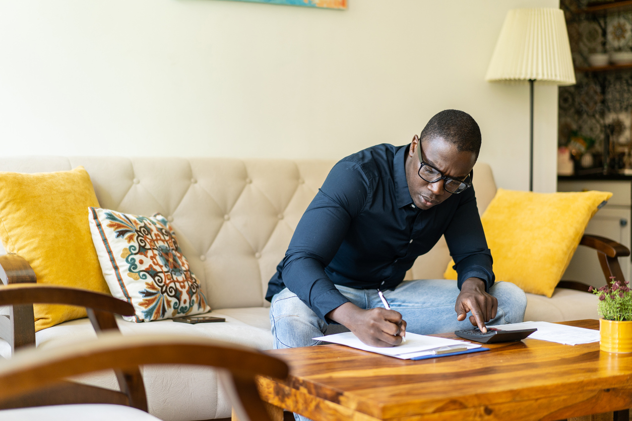 A worried man is adding up his household expenses