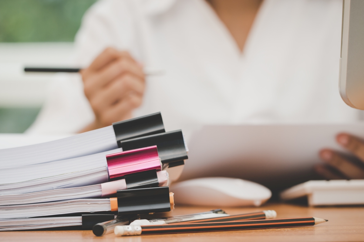 Stacks of clipped paperwork with woman in background