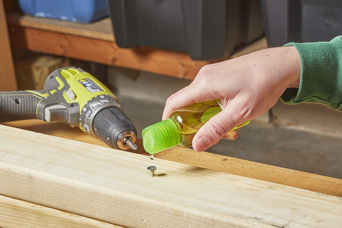 A person pouring a drop of liquid abrasive onto the head of a stripped screw.