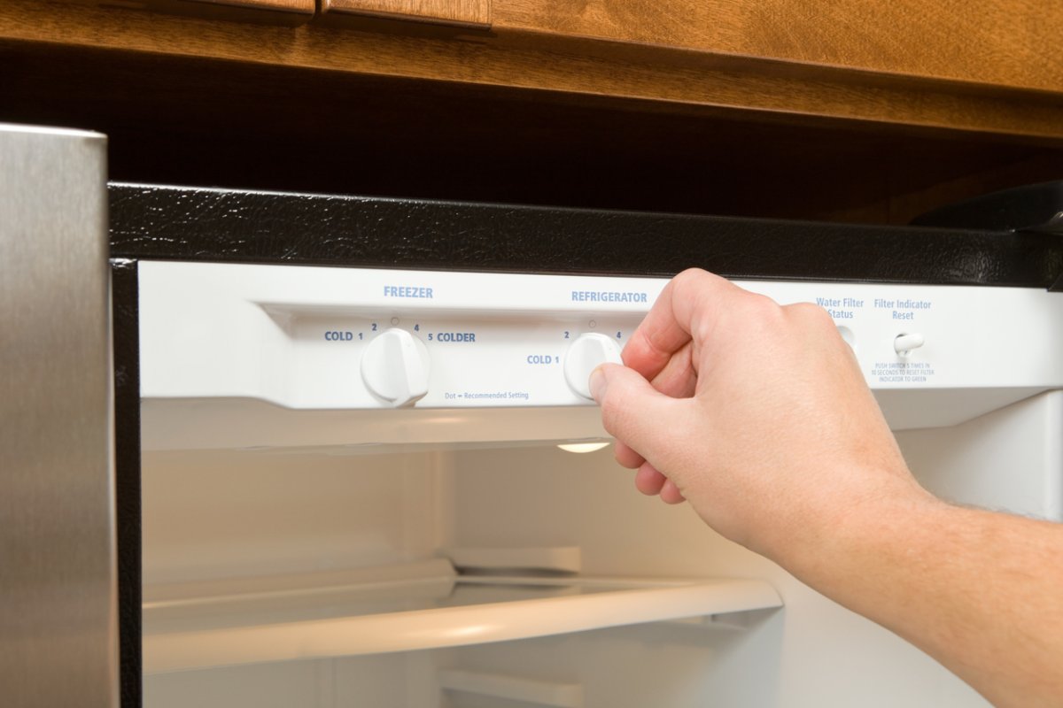 Person adjusts the temperature on a freezer thermostat. 