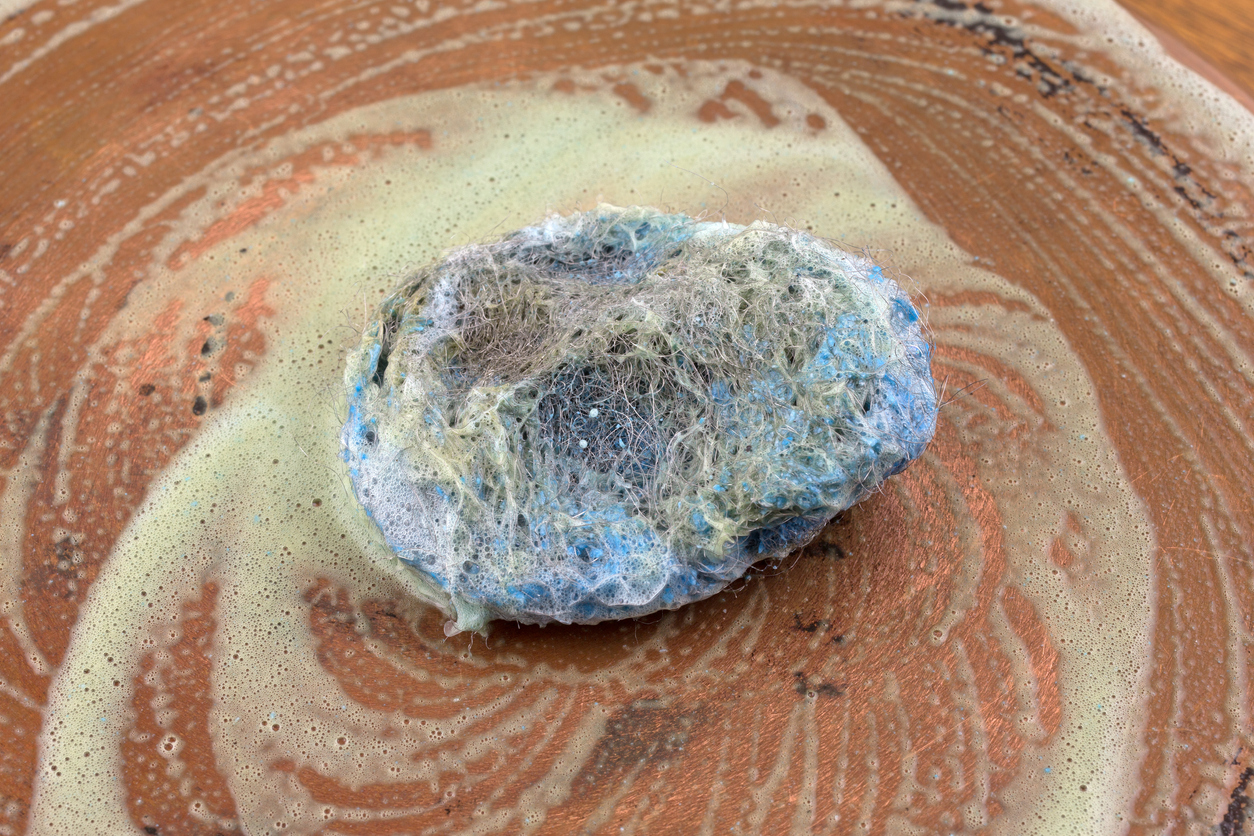 Washing copper pan with vinegar cleaning solution and sponge.