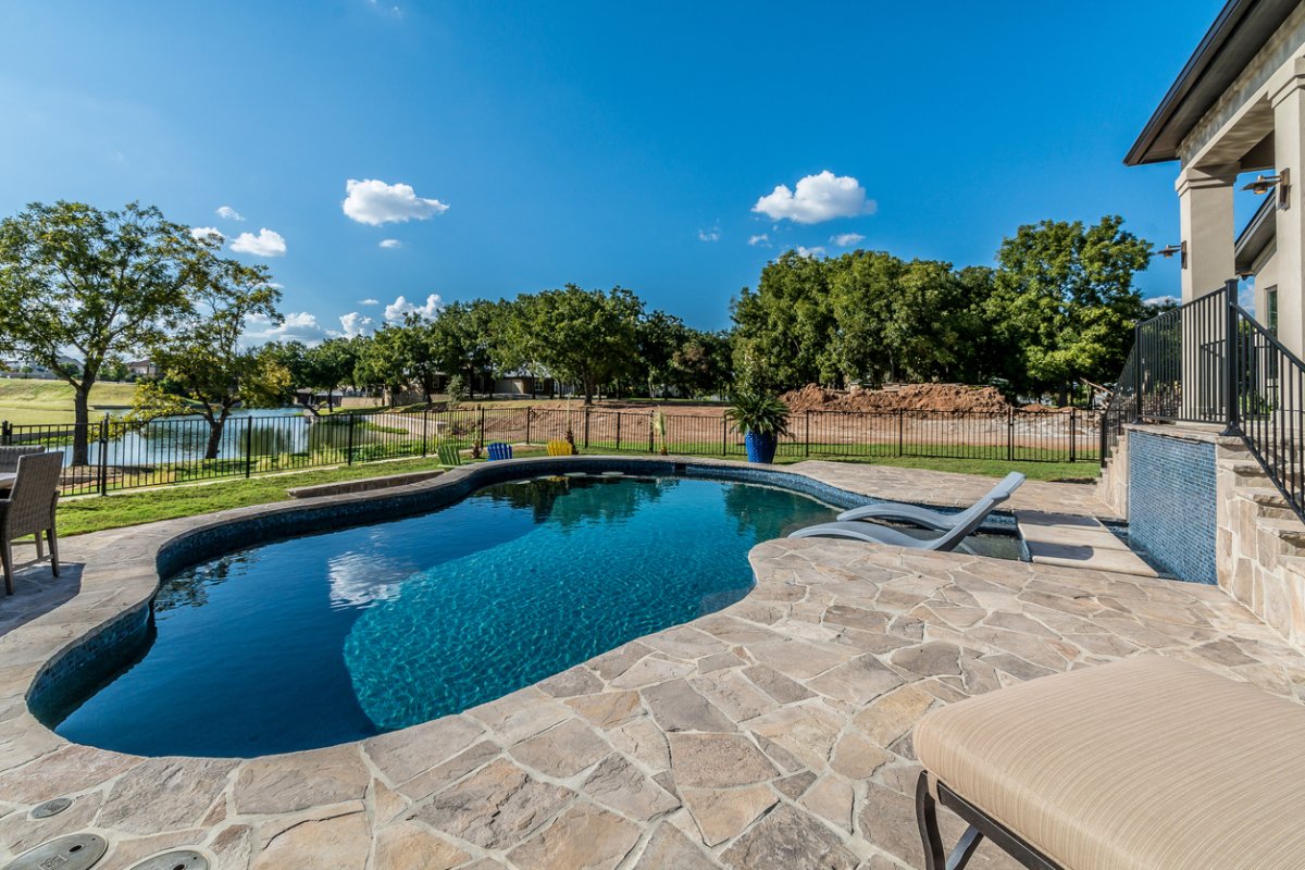 A view of a beautiful in ground pool on a bright summer day.