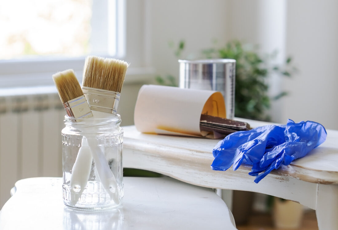 A group of furniture painting tools on top of a small table that is ready to be painted.