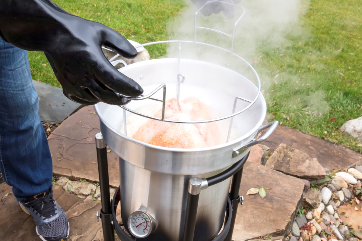 comment faire frire une dinde - main gantée sortant la dinde