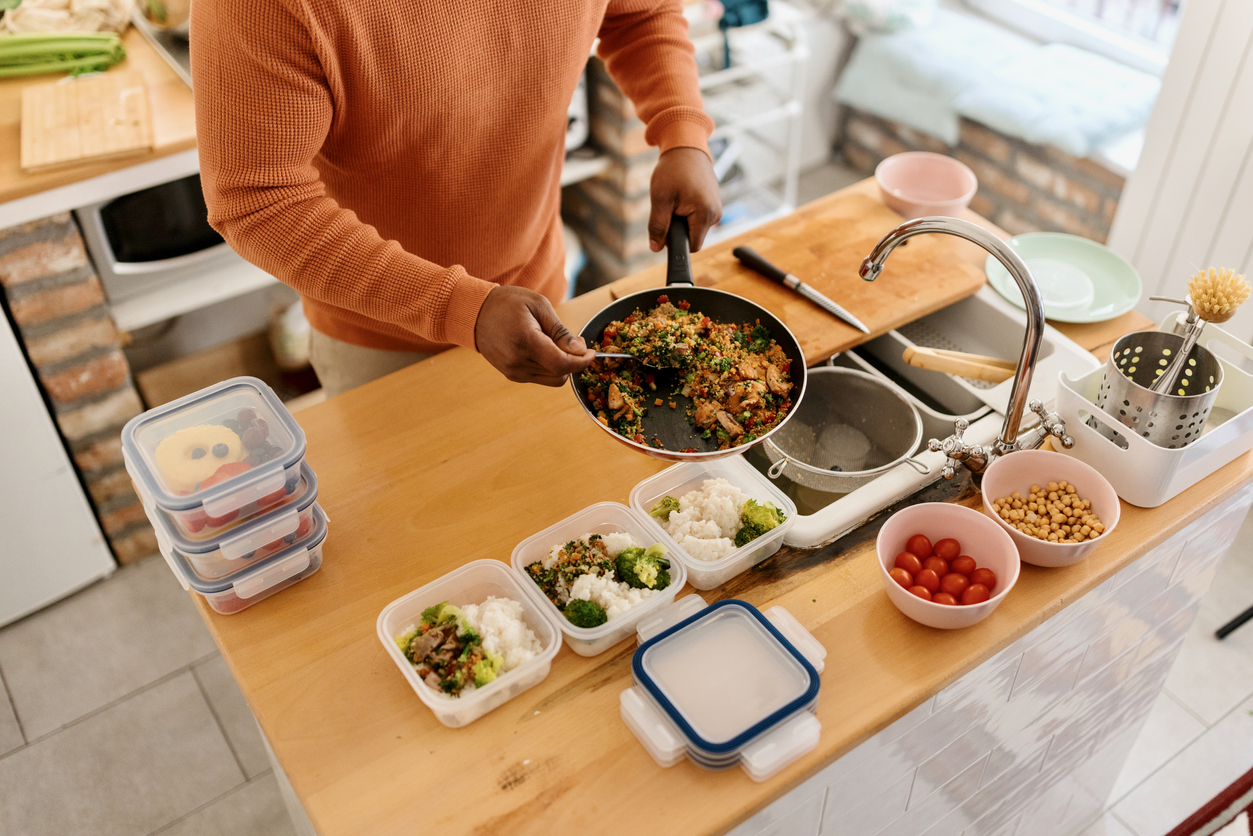 Homme préparant ses repas pour la semaine à venir à l'aide du plan de repas établi par sa nutritionniste.