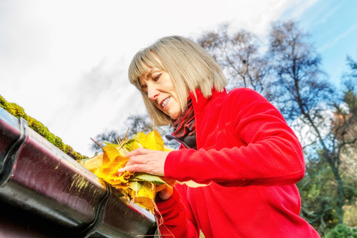 Woman cleaning gutters by hand.