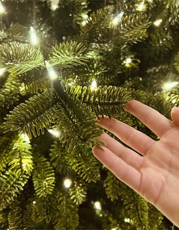 A person touching the molded fir needles of the Balsam Hill Fraser fir flip tree.