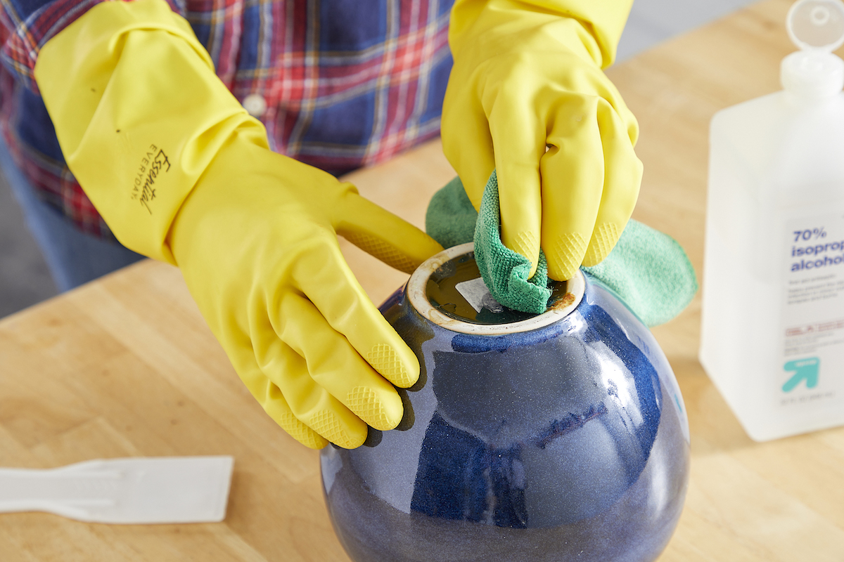 Woman wearing rubber gloves uses rubbing alcohol to remove a price sticker.