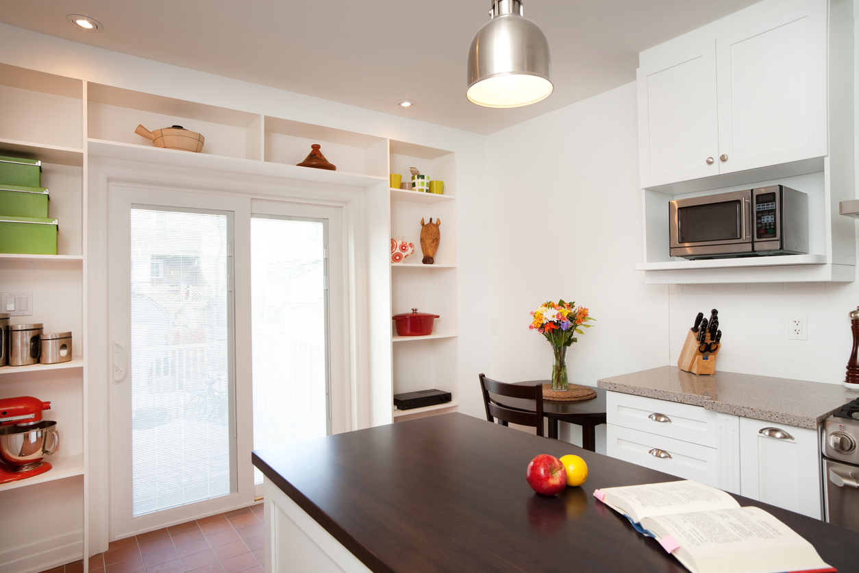 Modern white kitchen with open shelves over and next to double doors.