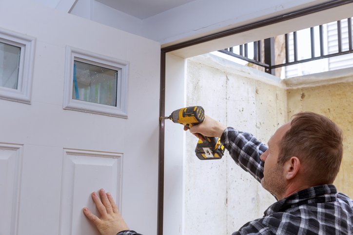 energy-efficient-tax-credit-man-with-drill-hanging-white-front-door-for-entrance