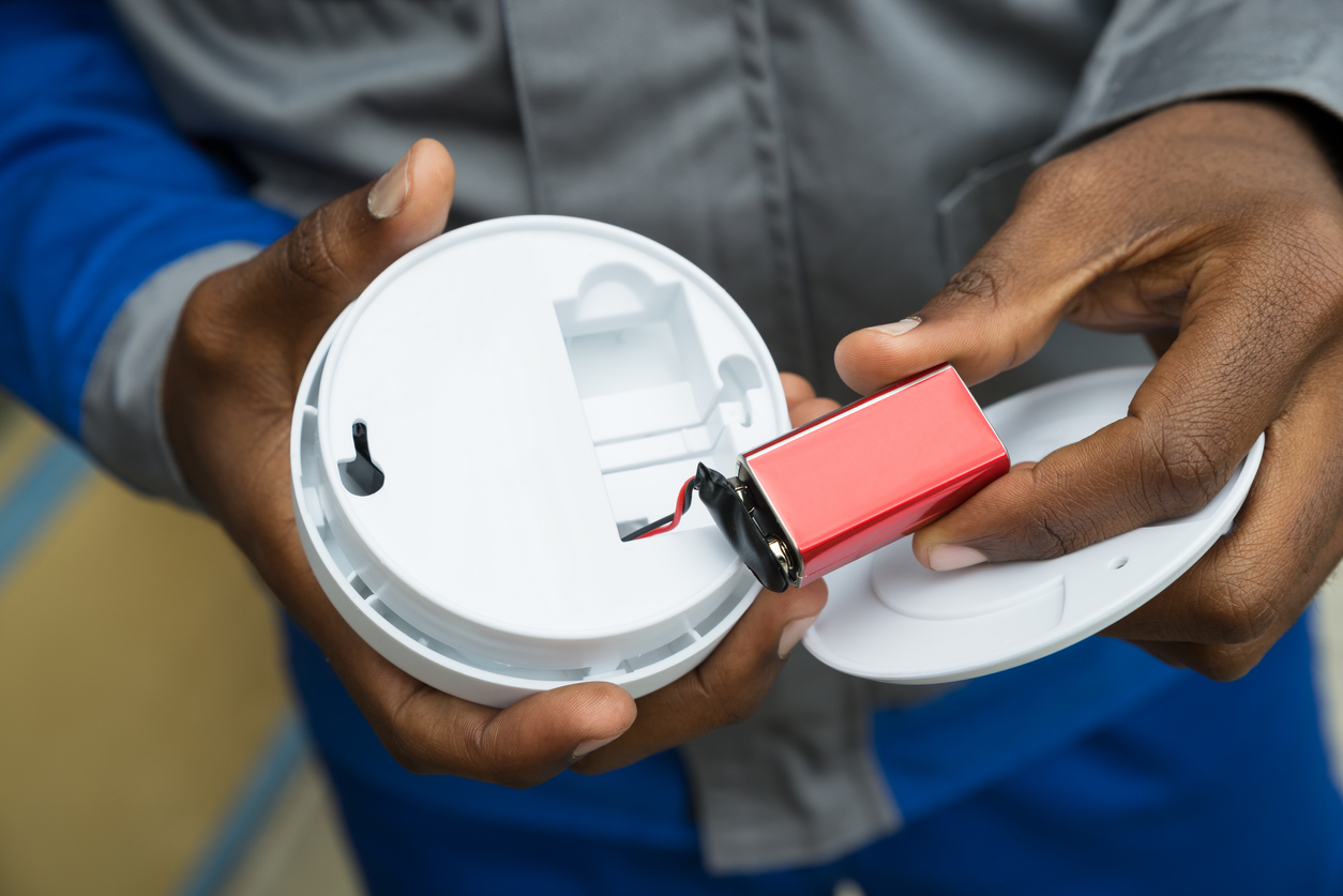 Close-up Of Electrician Hands Removing Battery From Smoke Detector