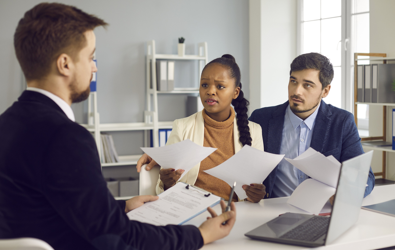 iStock-1329553958 couple héritant d'une maison se réunit avec un avocat tout en examinant des documents