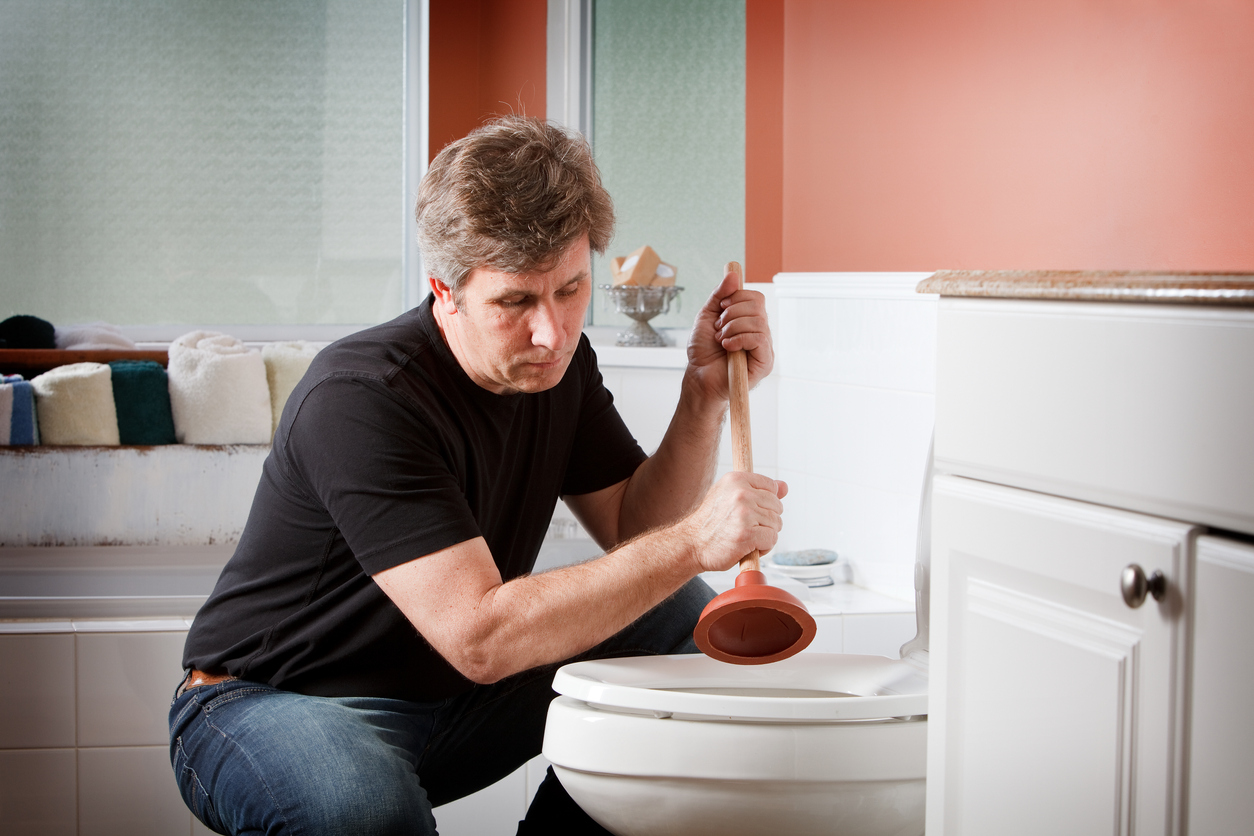 homme d'âge moyen débouchant les toilettes