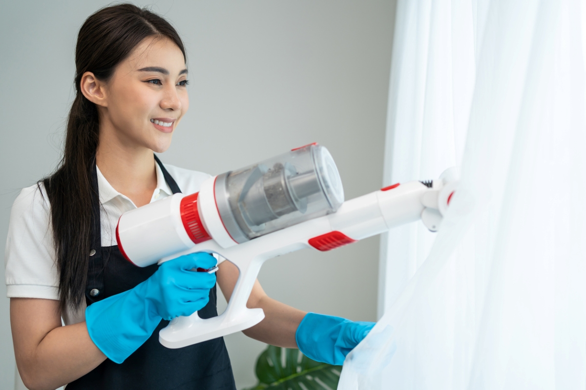 Femme utilisant un aspirateur sur des rideaux