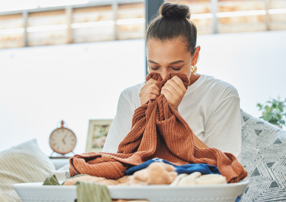 Photo d'une jeune femme reniflant une brassée de linge propre