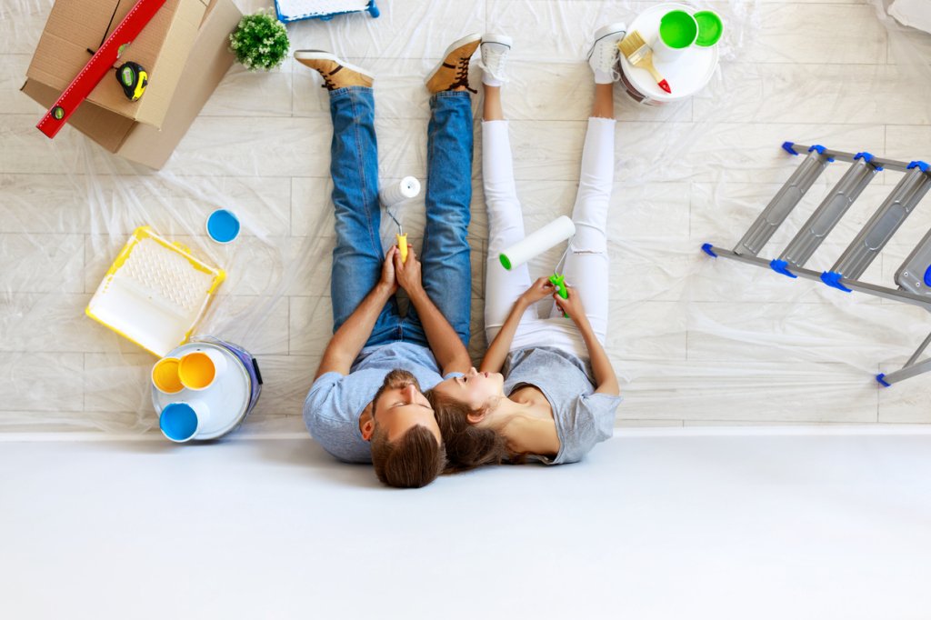 young tired couple is repairing and painting the wall at home