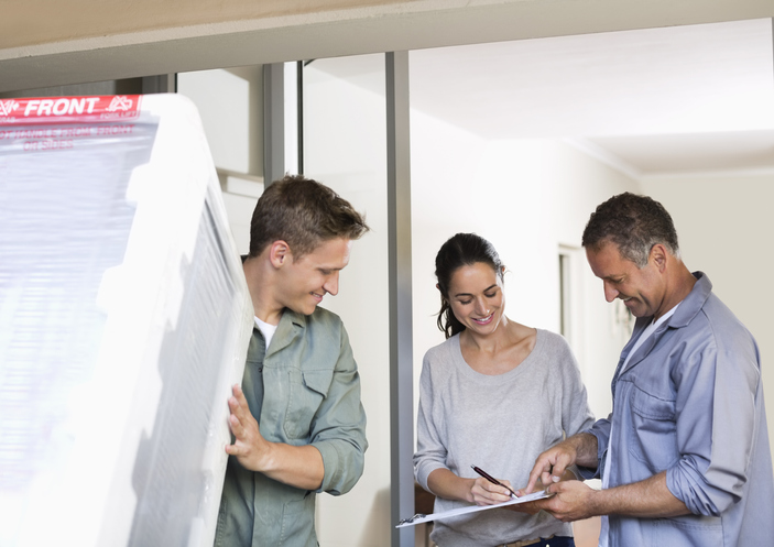 energy-efficient-tax-credit-woman-signs-for-a-new-appliance-with-two-workmen