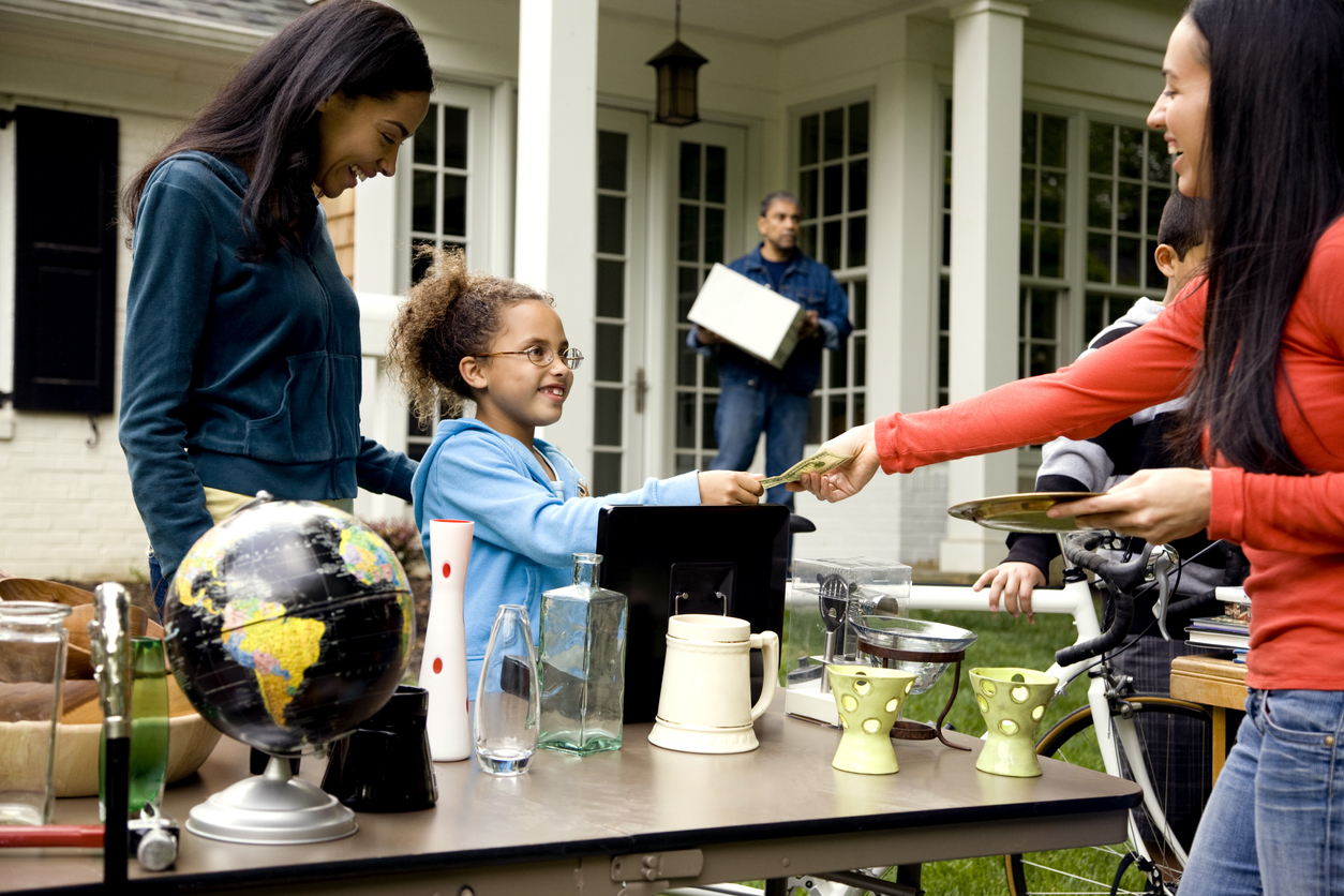 Two young women and a young girl shop around a yard sale table.