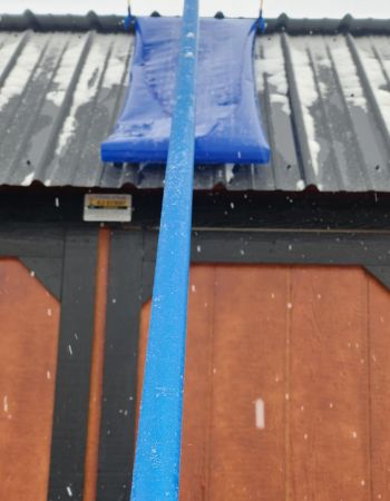 L'Avalanche ! Un râteau de toit est en cours de test pour retirer la neige légère d'un toit en métal.