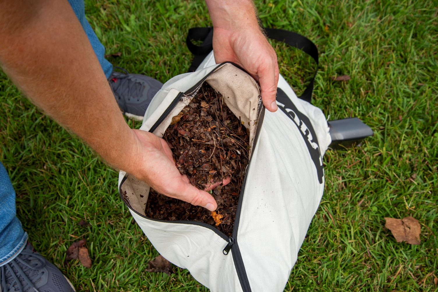 Une personne plongeant la main dans un sac rempli de feuilles broyées créé par la meilleure option d'aspirateur à feuilles