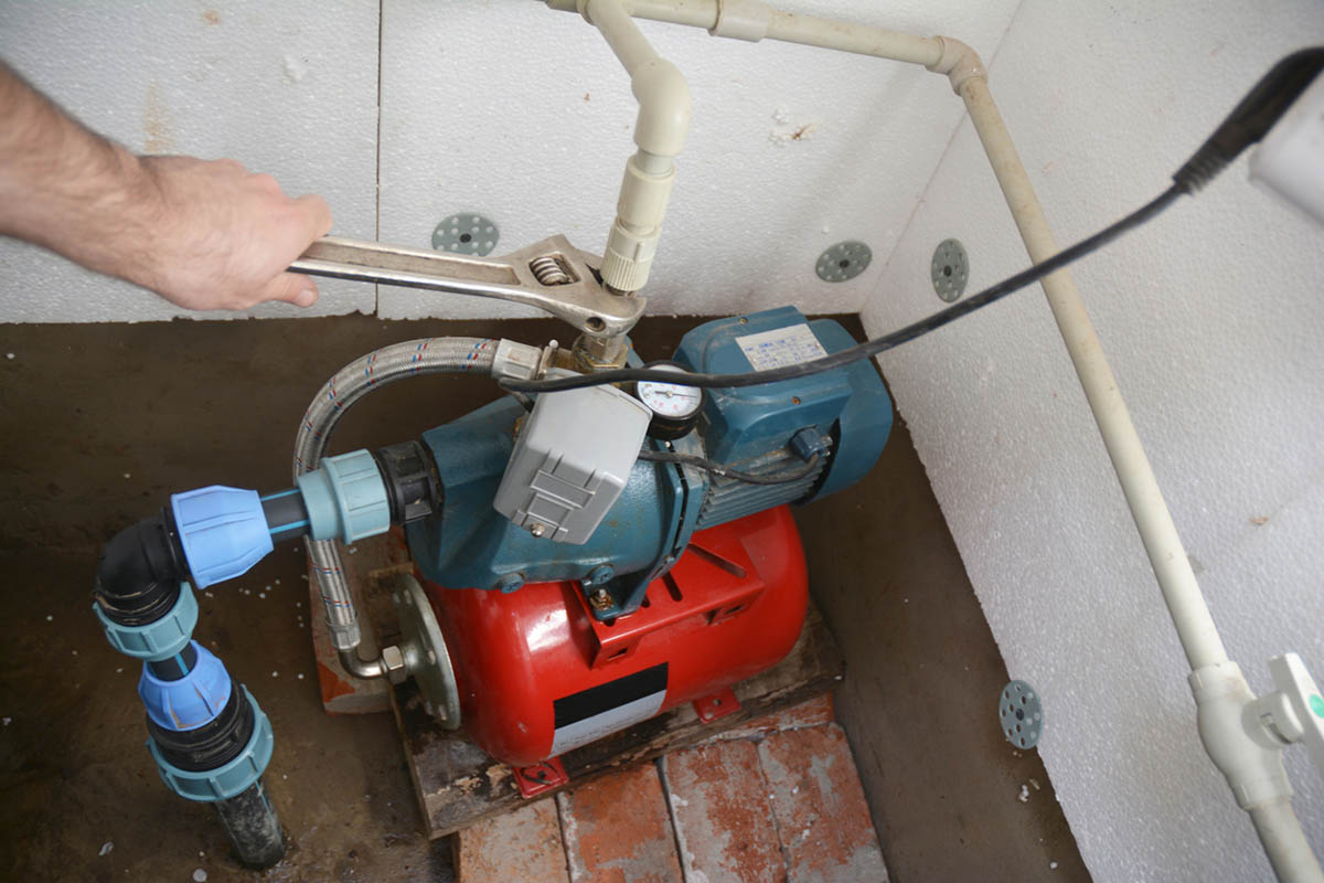 A man uses a wrench to adjust the best shallow well pump option