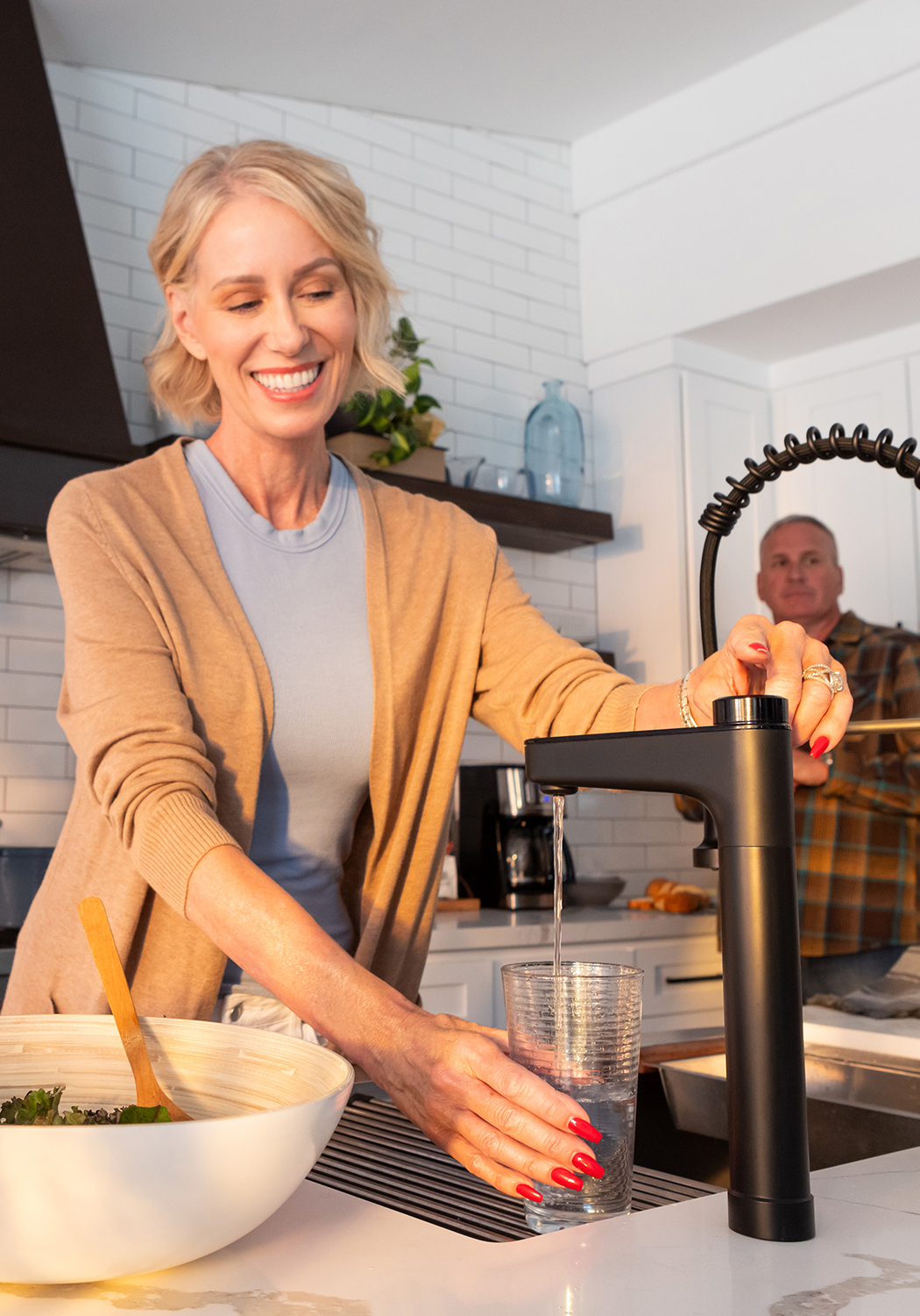 Woman filling a glass of filtered water from the Waterdrop X16 smart faucet