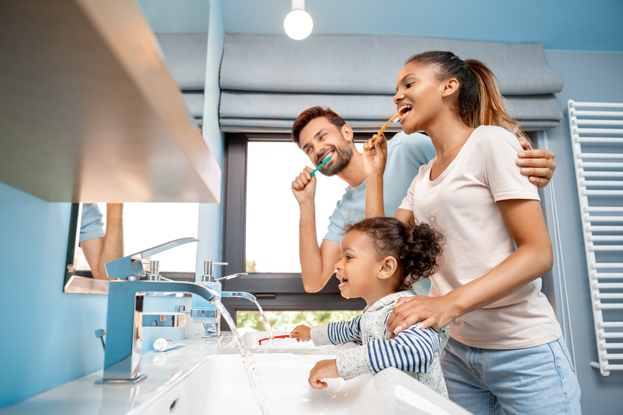 Mother, father and daughter brushing teeth in bathroom