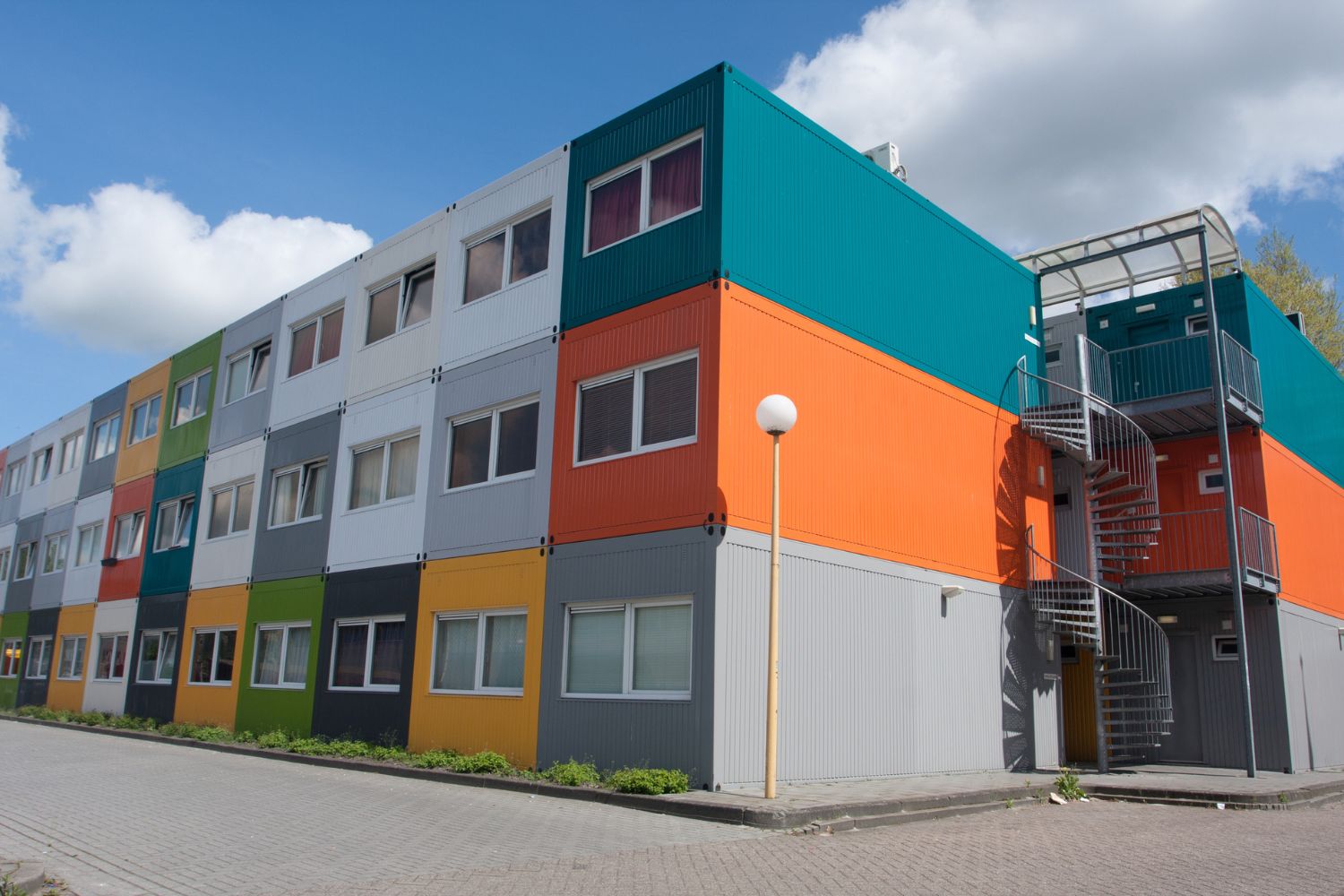 An apartment building made of multicolored container homes stacked three high.