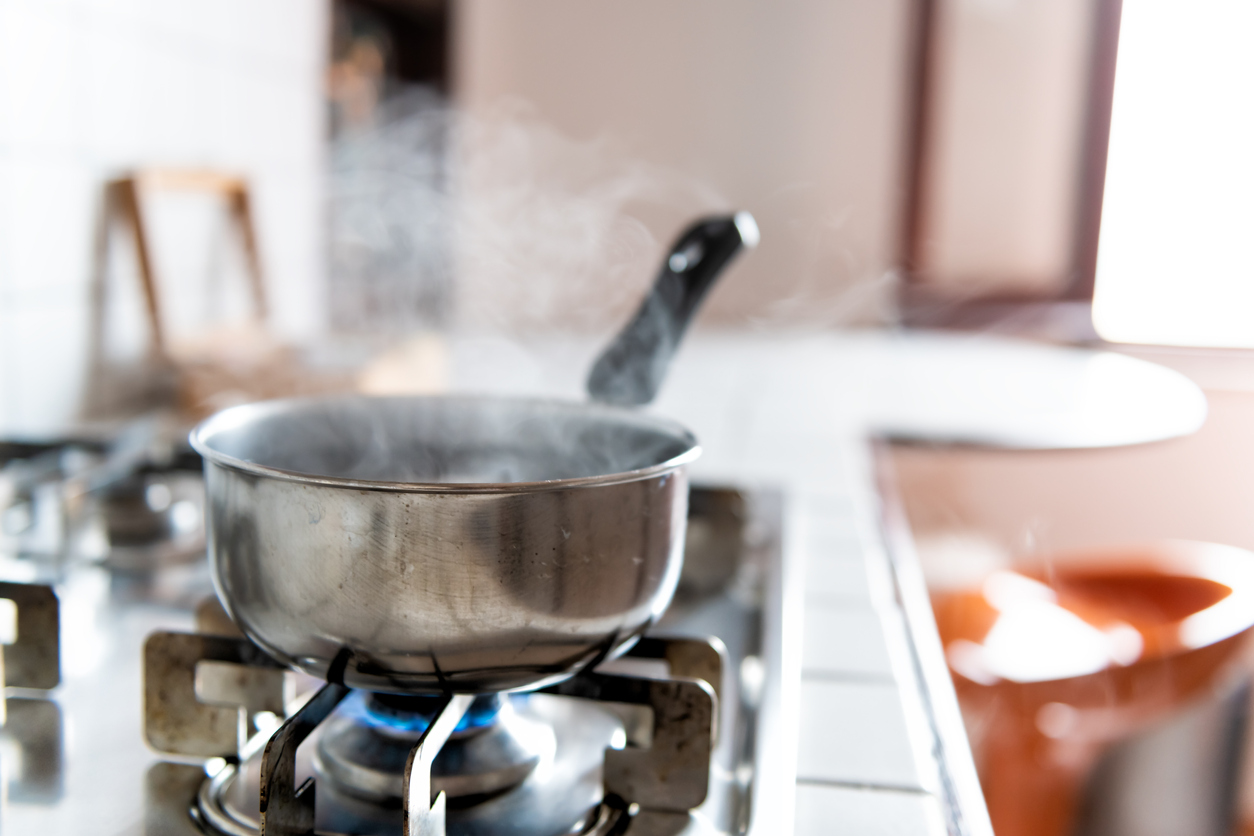 small pot on stove with boiling water and rising steam