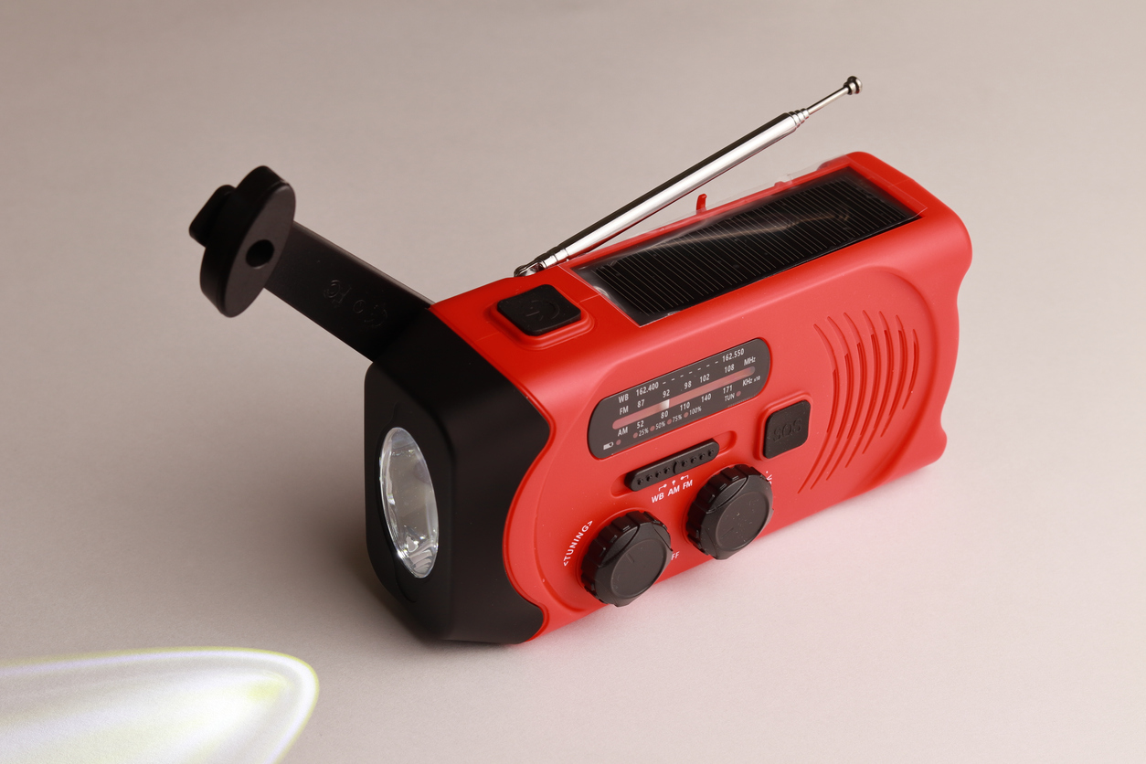 Petite radio portative rouge rechargeable par panneaux solaires ou manuellement avec une manivelle. Lampe de poche incluse